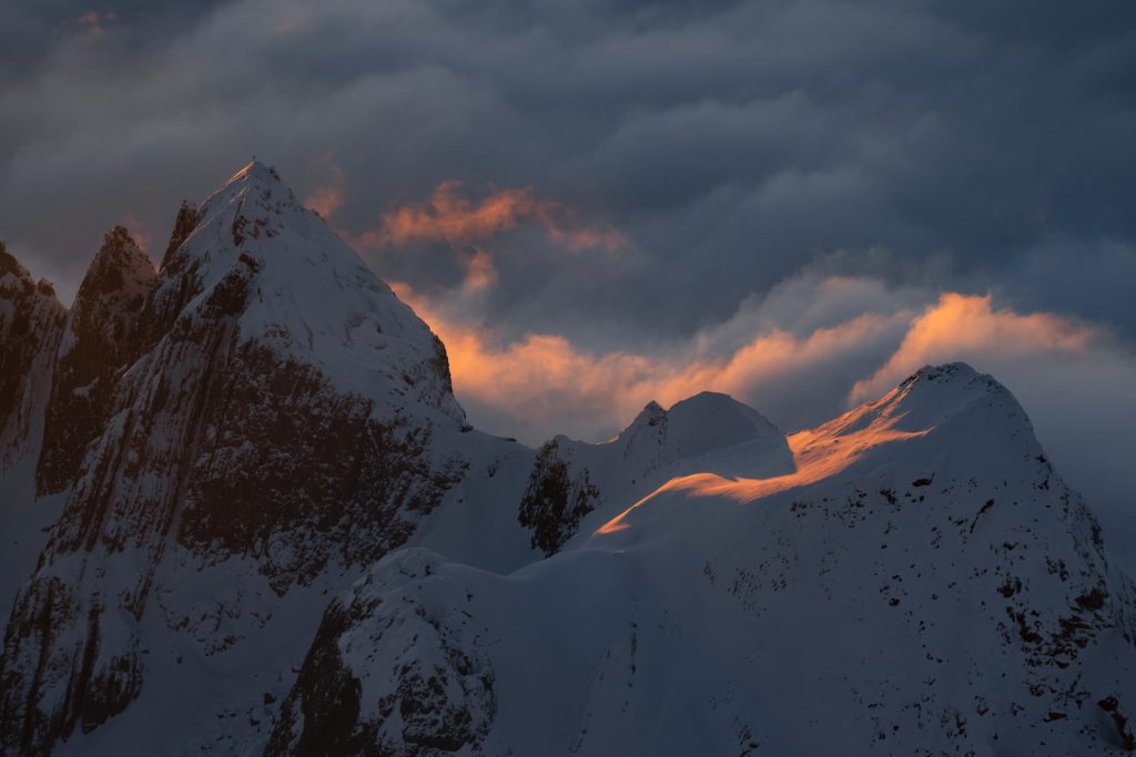 a mountain covered in snow under a cloudy sky